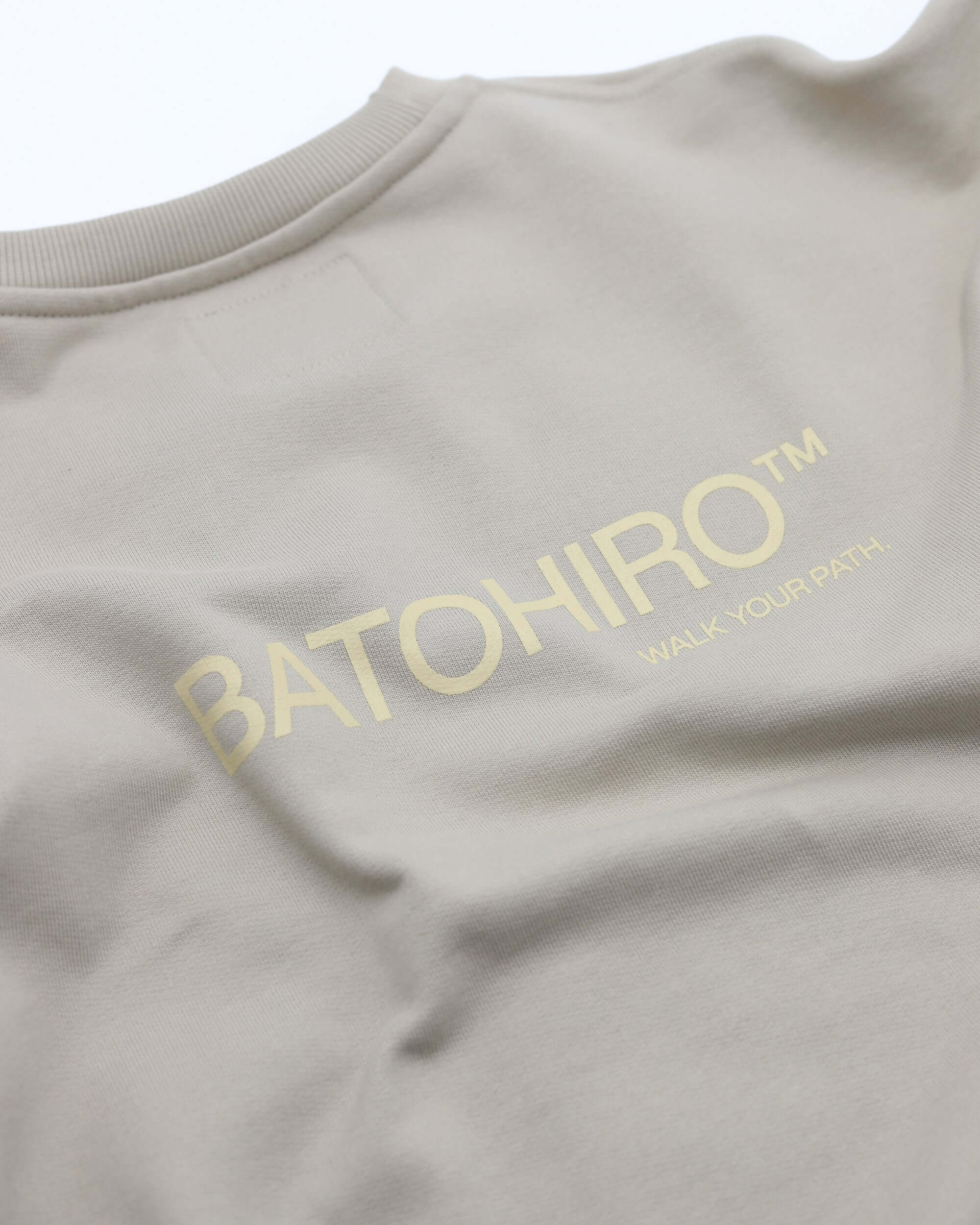 Detail na béžovou mikinu crewneck Batohiro s potiskem na zadní straně. Unisex styl, příjemný materiál.