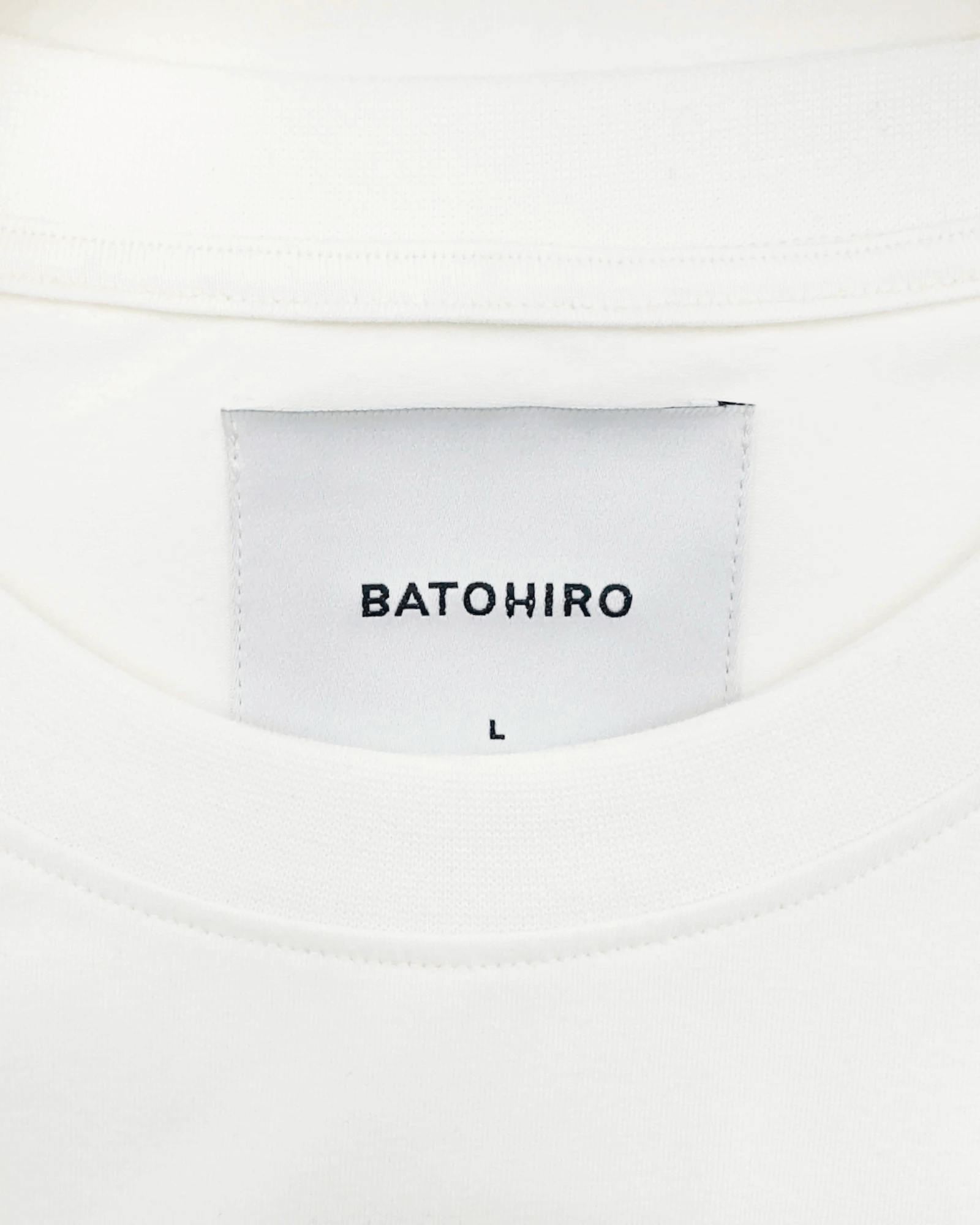 Detail of the label on the White Tiger - Oversized Tee showing the brand BATOHIRO and size L.