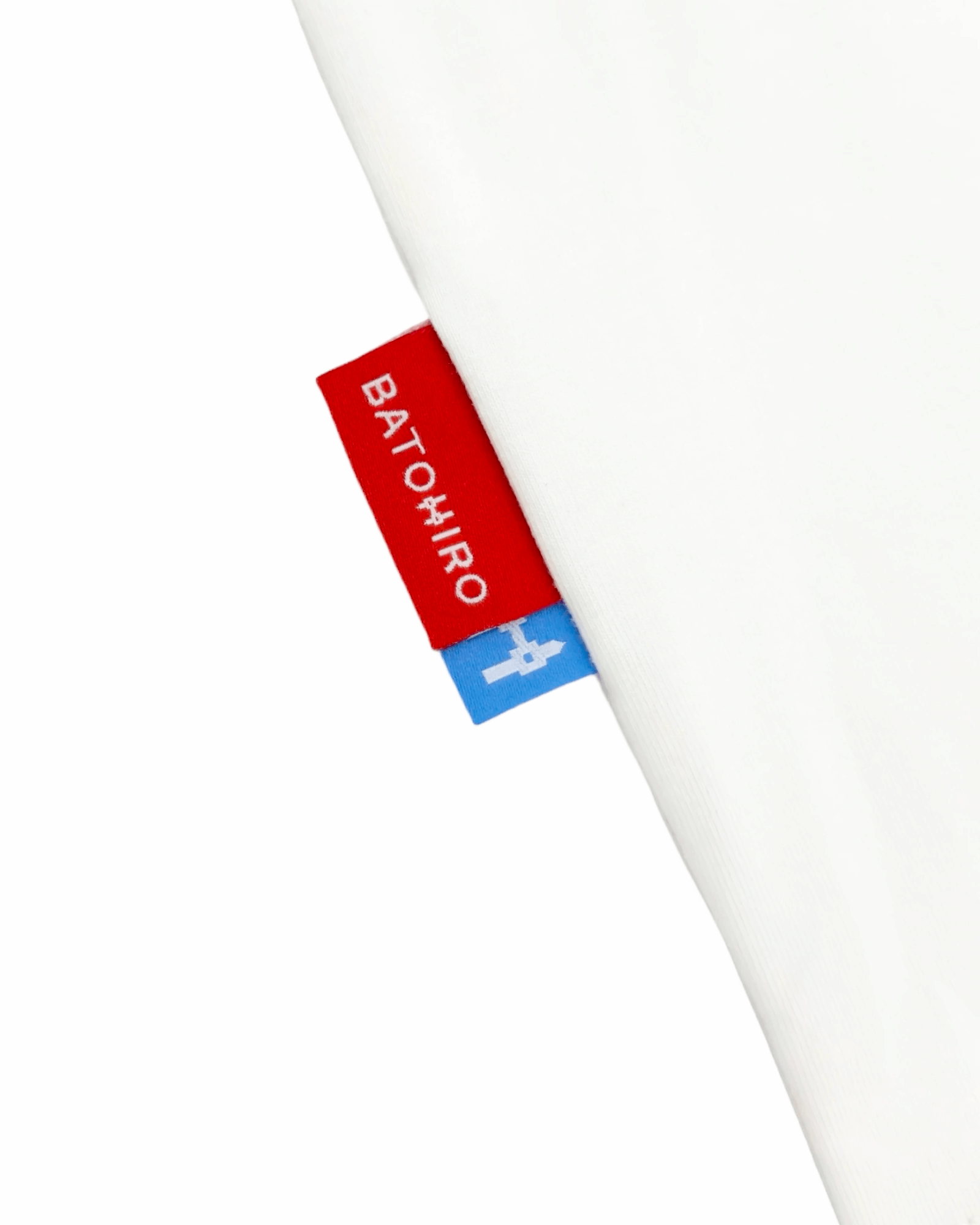 Close-up of Batohiro brand labels on a white cropped oversized tee, showcasing unique design and quality.