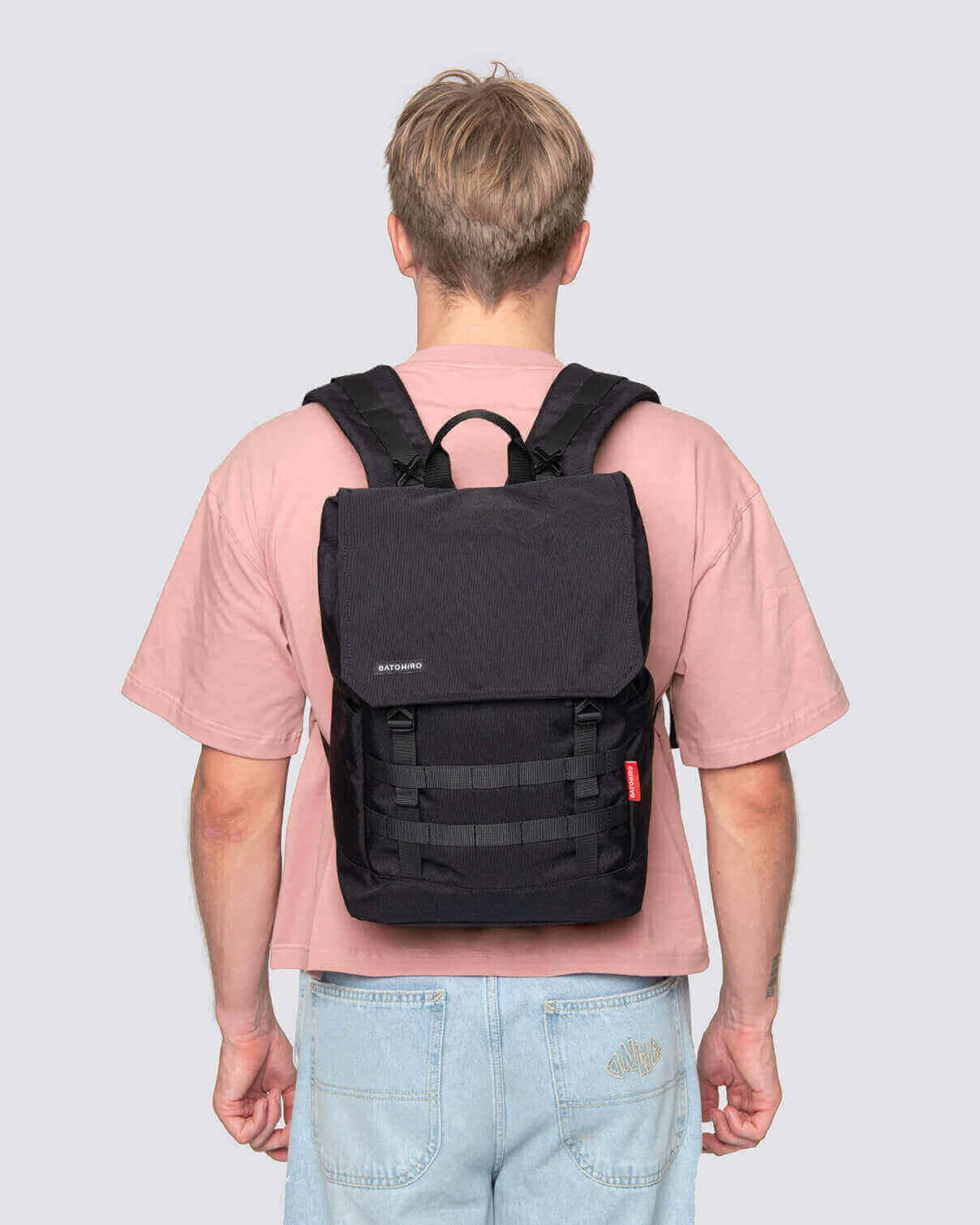 Stylish man wearing a black Minato Lite backpack, showcasing its practical design and adjustable features.