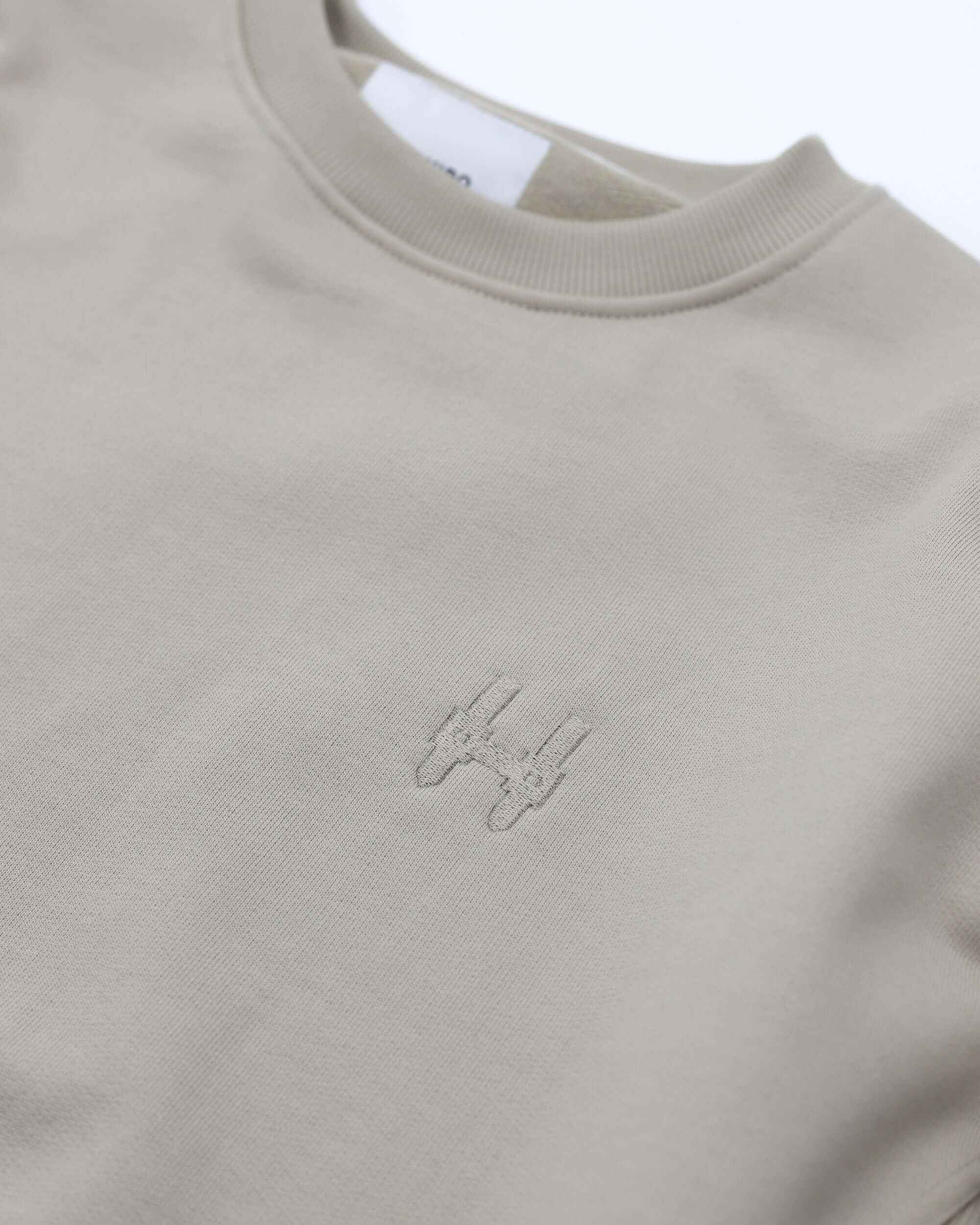 béžová mikina crewneck s jemným logem na hrudi, vyrobena z prémiové organické bavlny.