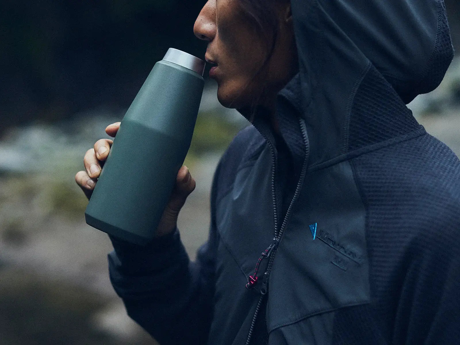 Person enjoying a warm drink from a stylish green trail tumbler outdoors. Perfect for outdoor activities!